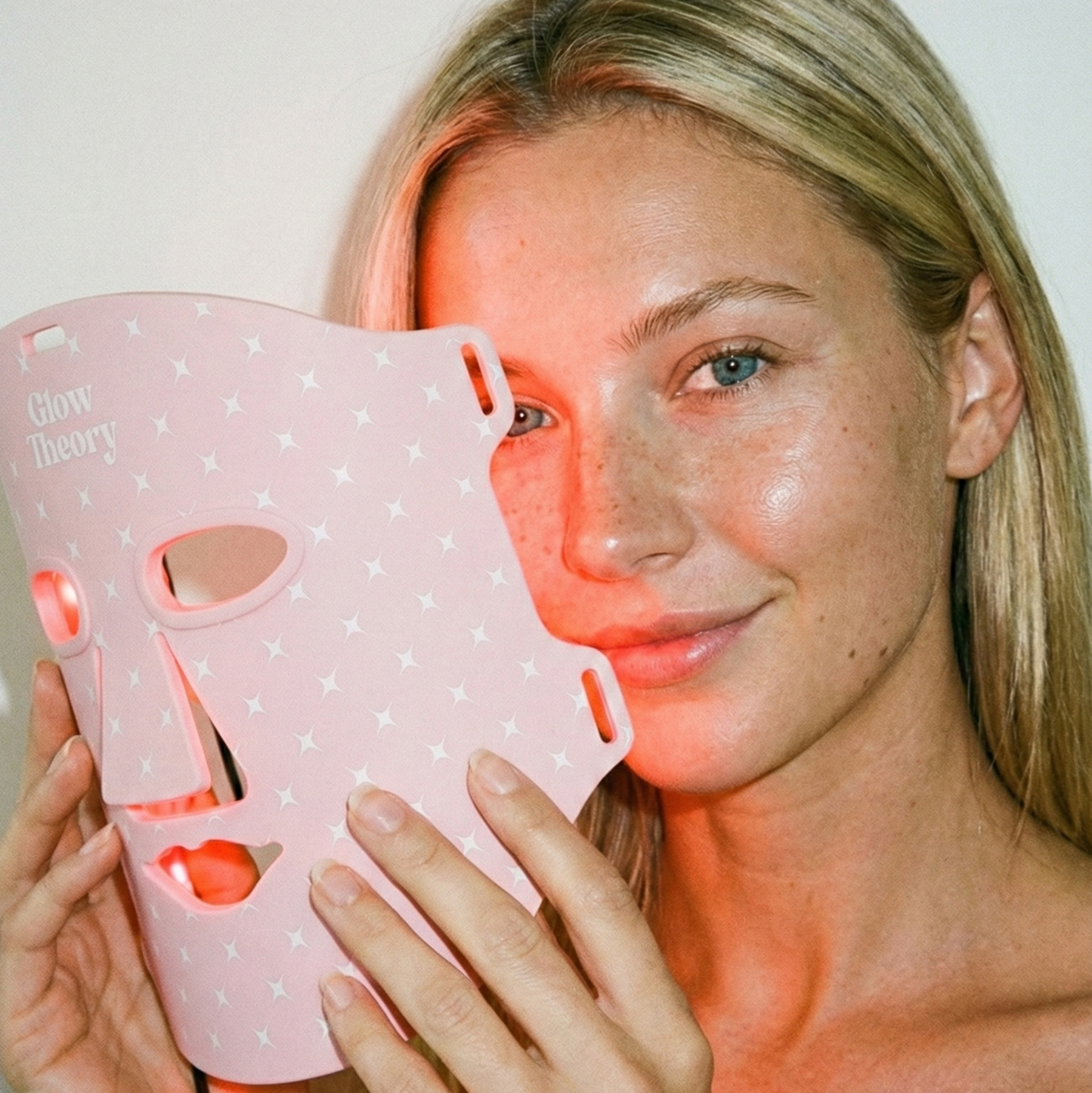 Model holding Glow Theory LED face mask. At-home red light therapy mask, skincare device