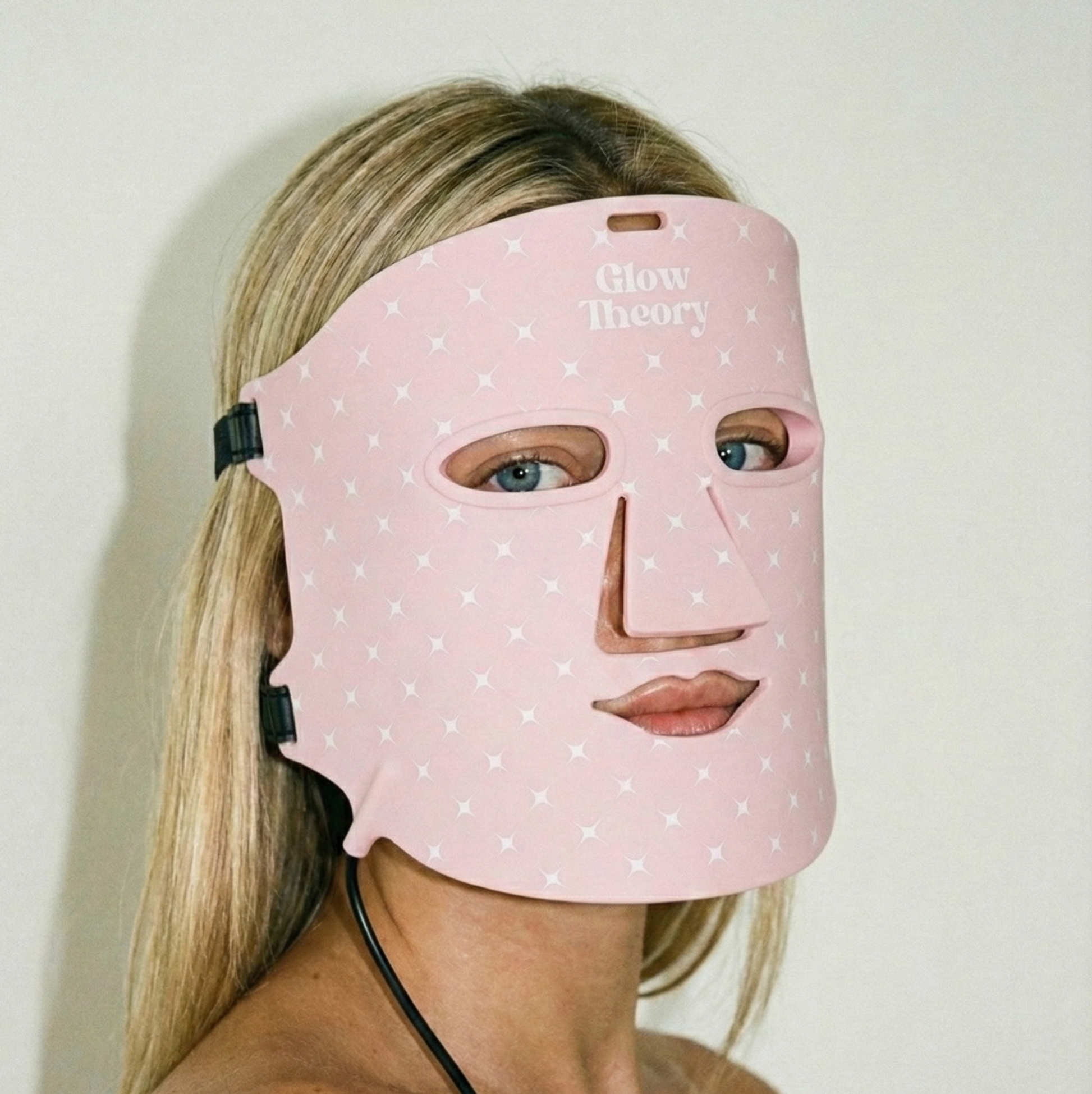 Model wearing a Glow Theory pink LED face mask. Side portrait 